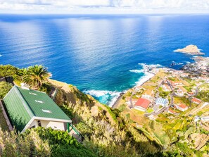 A coastal view with a building on a cliff overlooking the sea. - Green Valley by Homie (Porto Moniz)