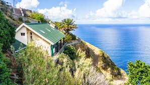 A coastal house with a green roof, a balcony, and a view of the sea. - Green Valley by Homie (Porto Moniz)