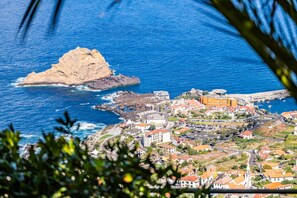 A coastal town with a prominent rocky island, a central plaza with buildings, and a view of the sea. - Green Valley by Homie (Porto Moniz)