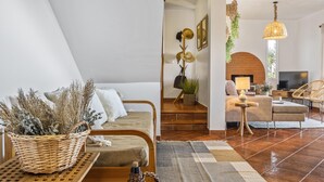 A modern living room with a sofa, a coffee table, and a TV. There is a staircase leading to an upper level. - Green Valley by Homie (Porto Moniz)