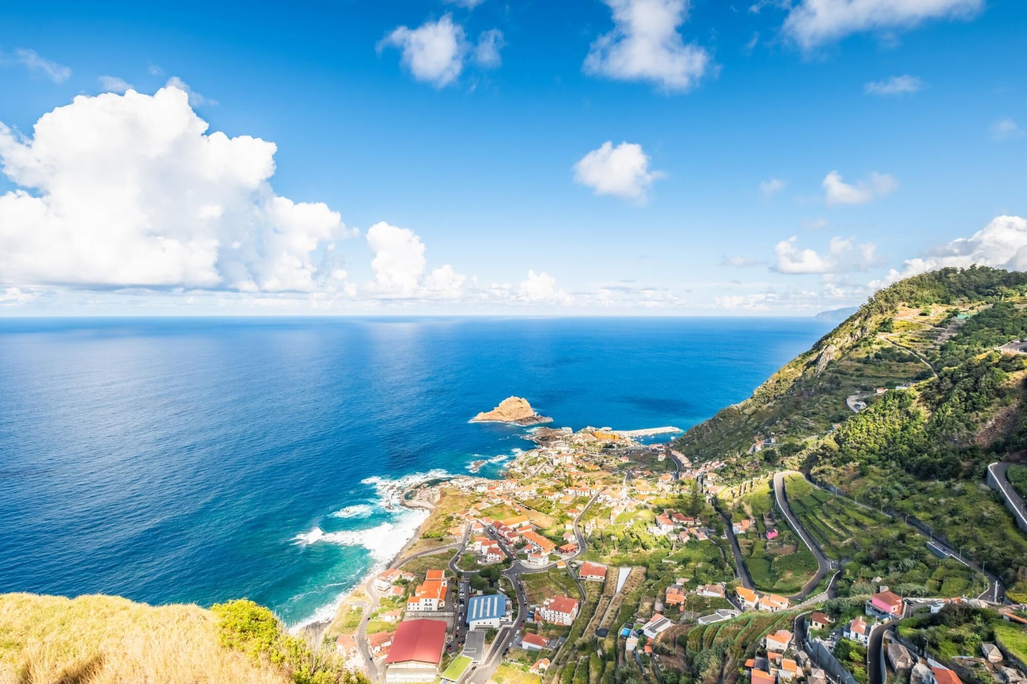 Un pueblo costero con vista al mar y una colina destacada.