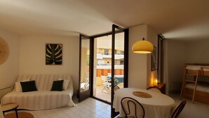 Un salon confortable avec un canapé, une table à manger et un balcon offrant une belle vue.