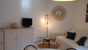 Un salon moderne avec un téléviseur à écran plat, un miroir rond et une lampe sur pied.