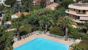 Vue aérienne d’une piscine entourée d’une végétation luxuriante et de bâtiments résidentiels.