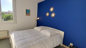Une chambre à coucher avec un lit, une commode, un radiateur et une fenêtre.
