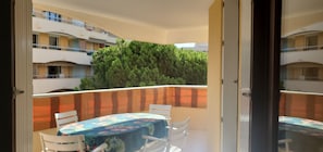 Enjoy dining al fresco with a view of the surrounding buildings and lush greenery from this balcony.