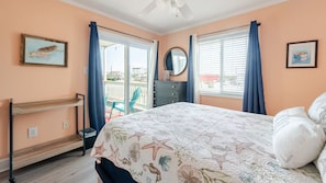 Une chambre à coucher comprenant un lit, une commode, une chaise, une fenêtre avec des rideaux et un balcon avec une chaise.