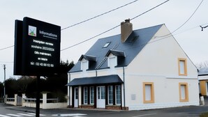 Um edifício de dois andares com telhado escuro e paredes brancas.