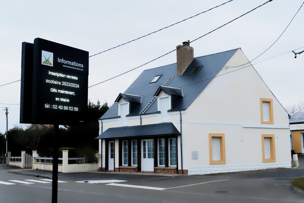 A two-story building with a dark roof and white walls.