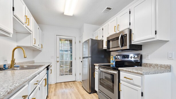 A modern kitchen with white cabinetry, stainless steel appliances, and a granite countertop.