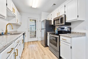 Une cuisine moderne avec des meubles blancs, des appareils en acier inoxydable et un plan de travail en granit.