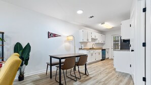 A modern kitchen with white cabinets, a wooden dining table, and two chairs.