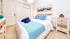 Ein Schlafzimmer mit Bett, Schminktisch, Nachttisch und einem Bild an der Wand.