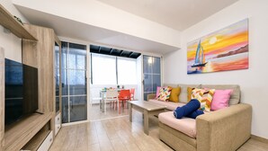 Ein modernes Wohnzimmer mit einer Couch, einem Fernseher und einem Gemälde eines Segelboots.