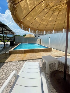 A swimming pool with a thatched umbrella, white lounge chairs, and a covered area with a metal roof. - Vacation House with Private Pool| El Rancho Vacation House (Cabo Rojo)