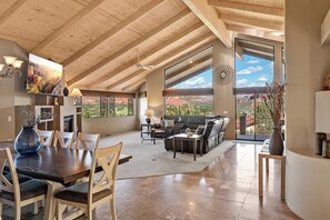 A spacious living area with a high ceiling, large windows, a fireplace, and a dining area with a table and chairs. - NEW! Red Rock Holiday, Airport Mesa, Decks, Views, SPA, Mins from Uptown (Sedona)