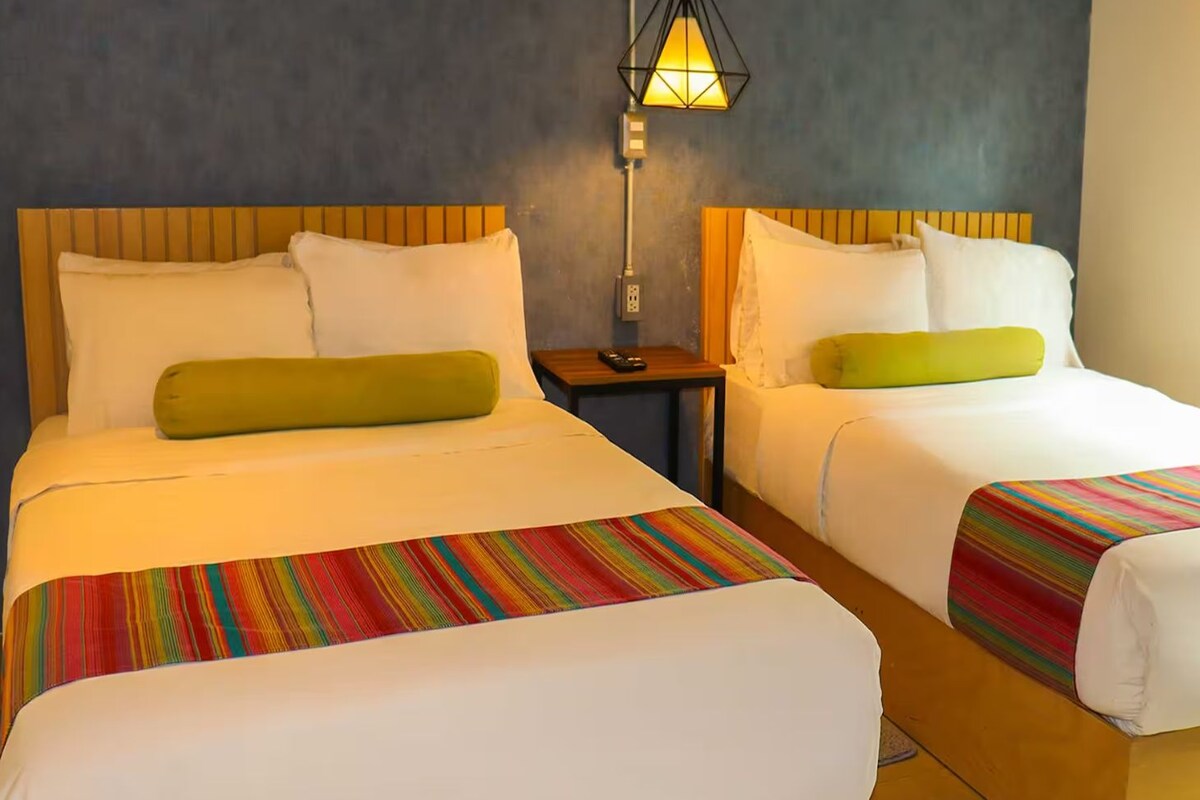Two beds with wooden headboards, white bedding, and colorful striped bedspreads.