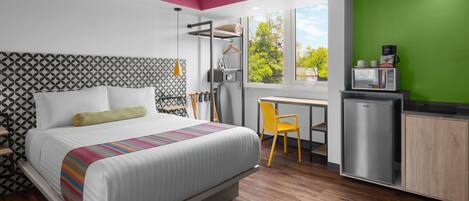 Une chambre moderne comprenant un lit, un bureau, une chaise et un coin cuisine.