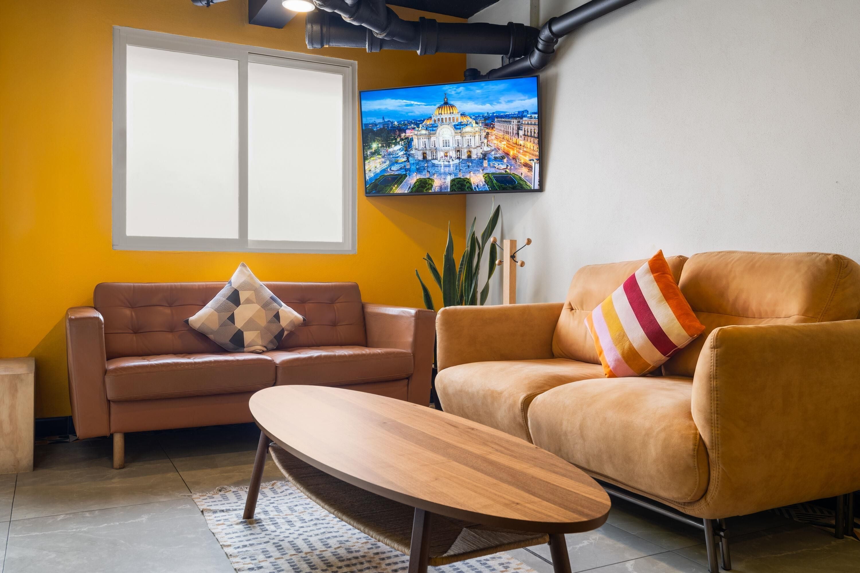 A living room with a sofa, a coffee table, and a television mounted on the wall.
