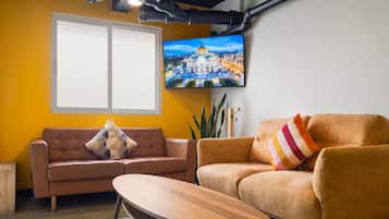 Un salon comprenant un canapé, une table basse et un téléviseur fixé au mur.