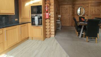 A log cabin interior with a kitchen, dining area, and a fireplace.
