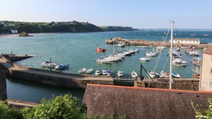 A harbor with boats docked, a stone wall, and a building with a red roof. - The Annexe (Saundersfoot)