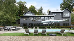 A modern two-story building with a swimming pool, outdoor seating, and a barbecue area. - Modern Country Home with Pool, Hot Tubs & Fire Pit - close to wineries & beach (Berrien Springs)
