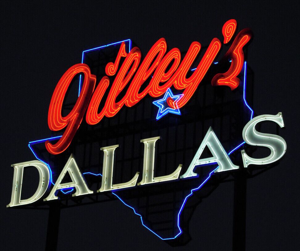 Um letreiro de neon com 'Guilfoy's Dallas' em vermelho e azul, e o contorno do Texas em azul.