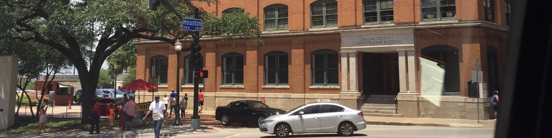 A large red brick building with arched windows and a sign for the Houston Independent School District.