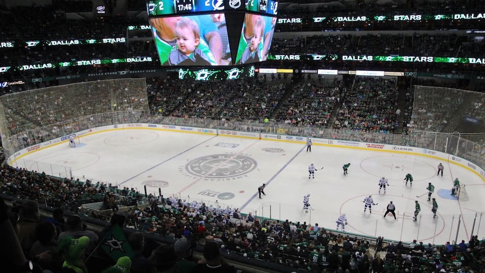Een overdekte ijsbaan met een bord waarop een wedstrijd tussen de Dallas Stars en een ander team wordt weergegeven.