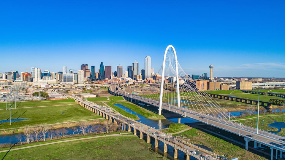 A city skyline with a prominent white bridge and a river.