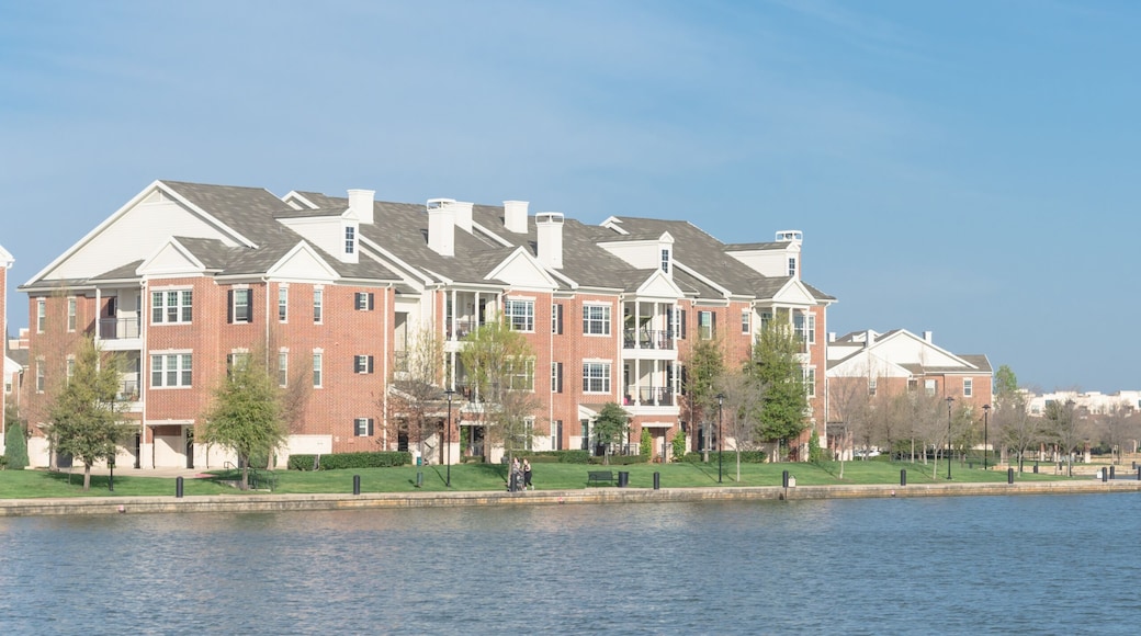 A waterfront with a row of brick buildings, a fountain, and a clear sky.
