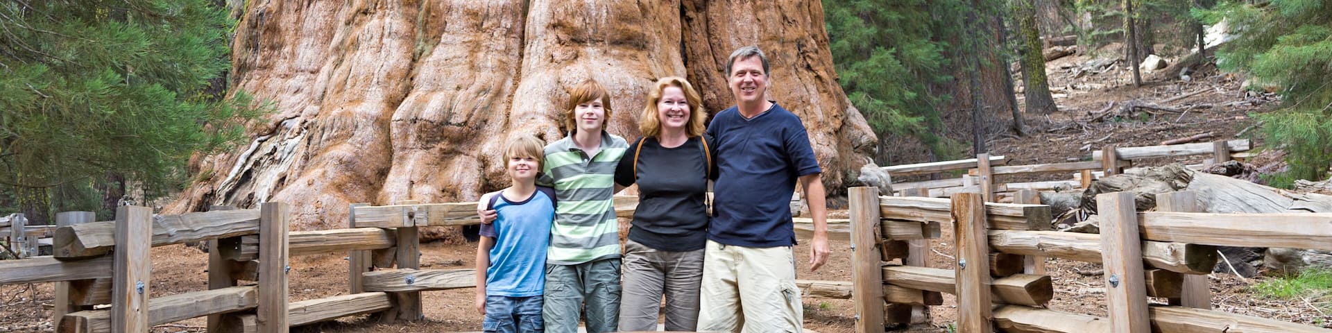 happy family enjoys posing in sequoia national park in front of general sherman sequoia tree