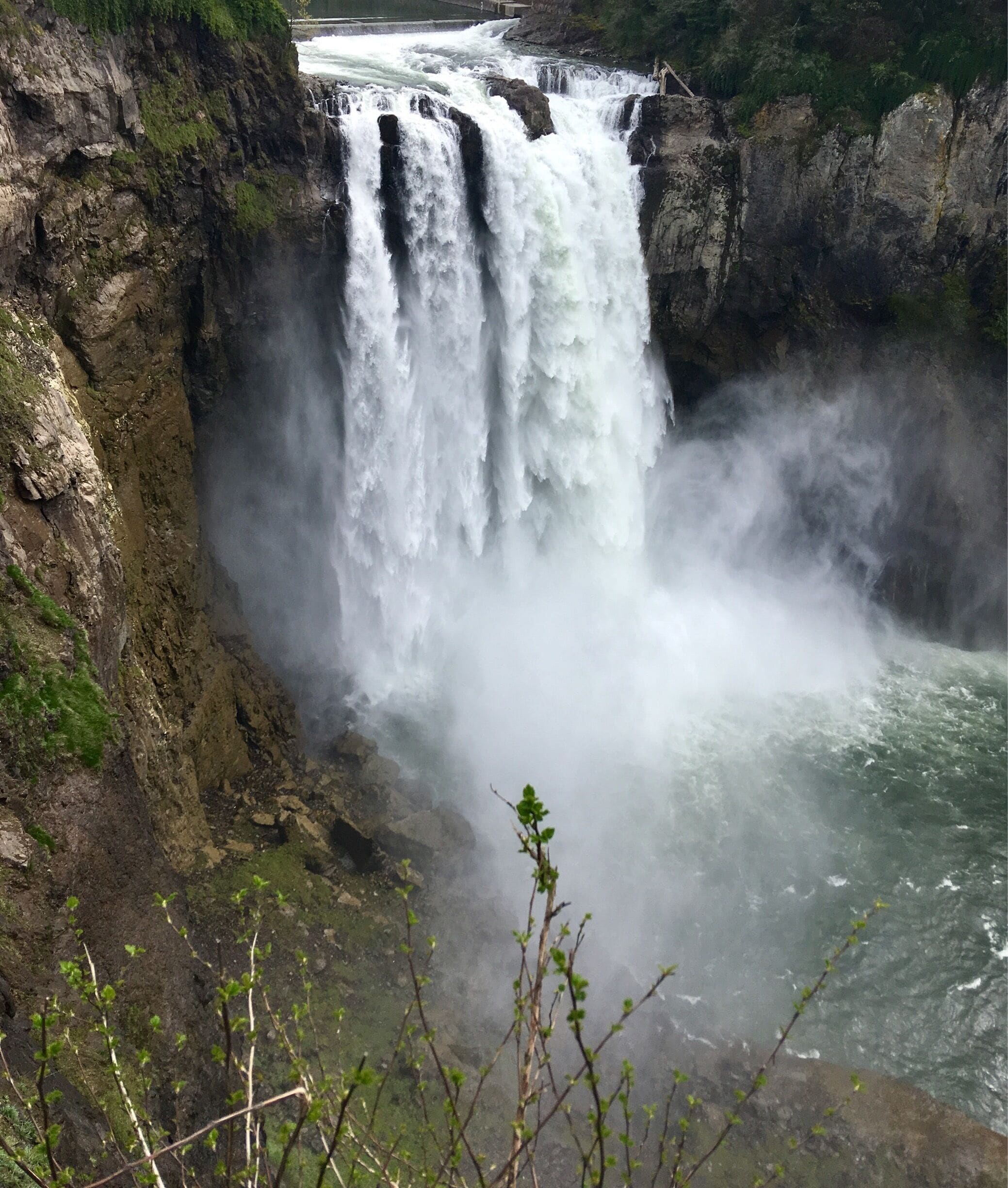 A powerful waterfall cascading down a rocky cliff into a river.
