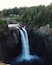 Una cascata si getta giù da una parete rocciosa, circondata da fitta vegetazione.