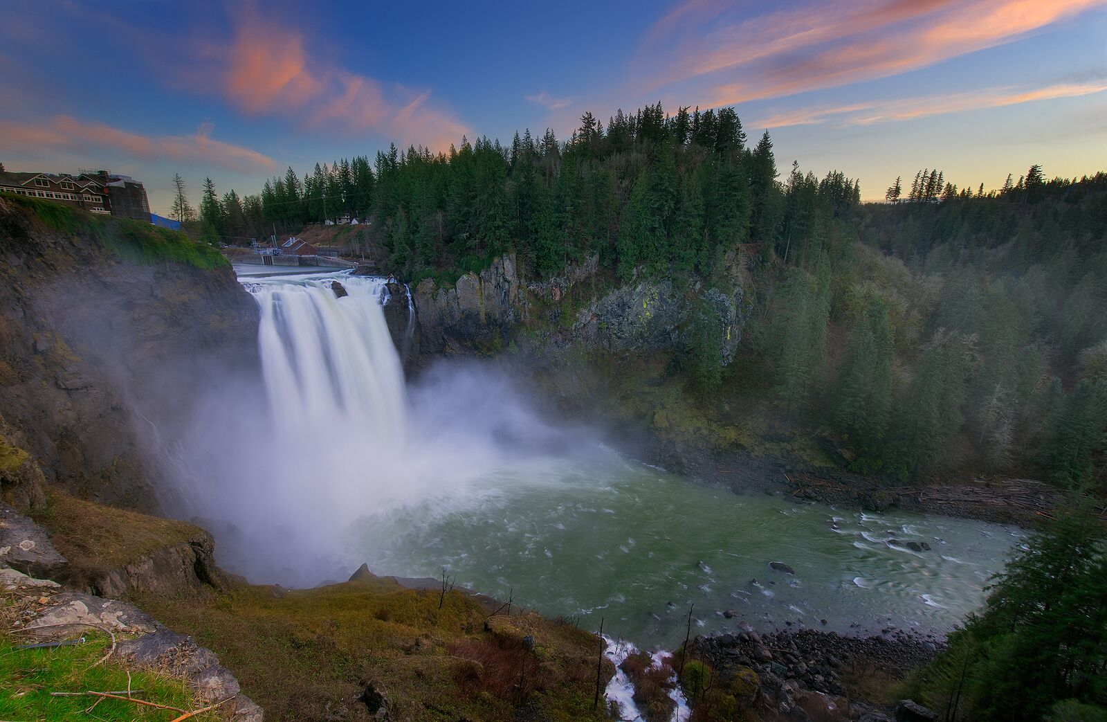 Una cascada que se precipita en un río rodeado de un bosque tupido.