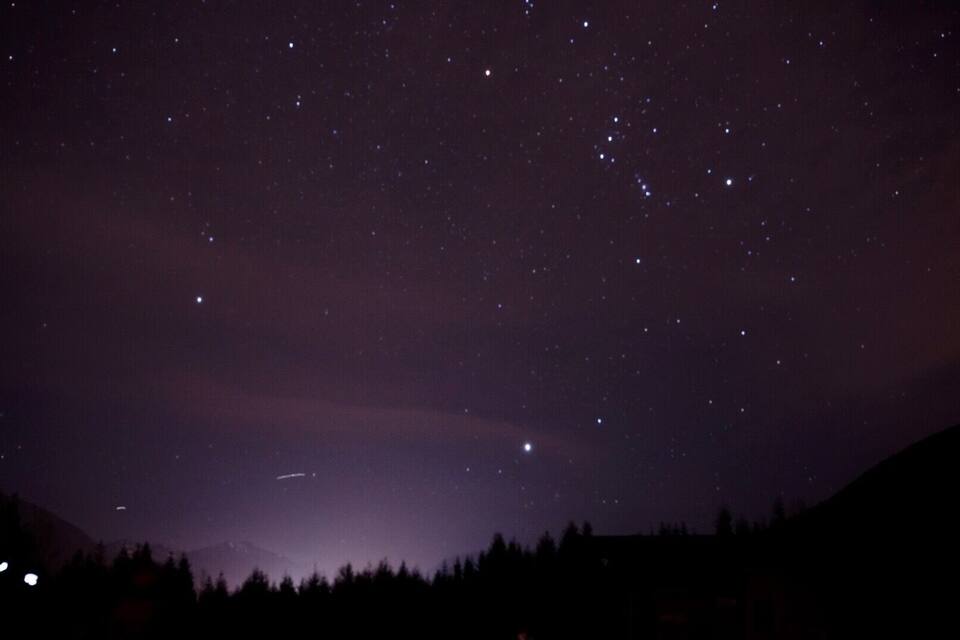 A starry night sky over a mountainous landscape with a visible Milky Way.