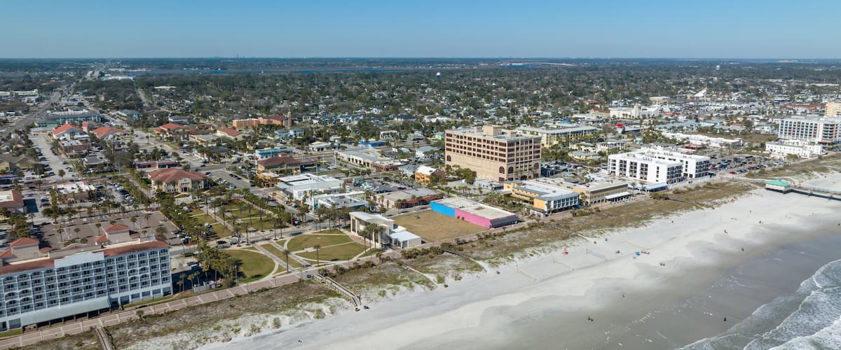 A coastal cityscape with a beach, buildings, and a clear sky.