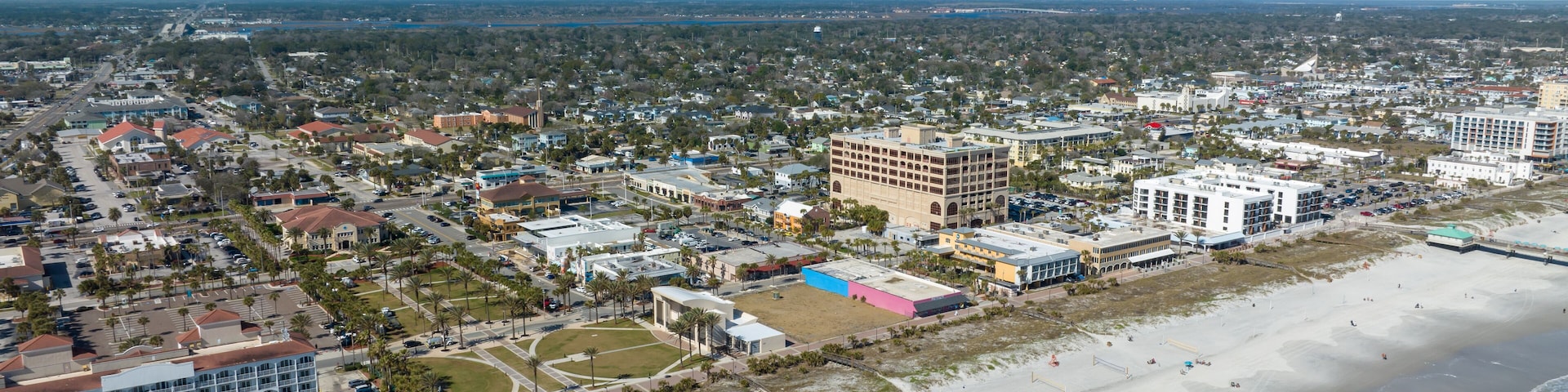 A coastal cityscape with a beach, buildings, and a clear sky.