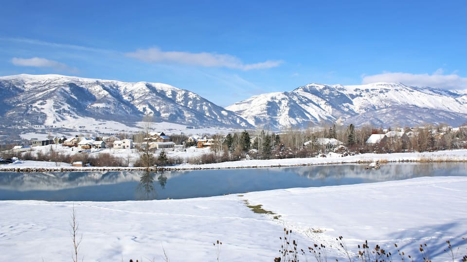 A snowy landscape with a lake, mountains, and a small town.