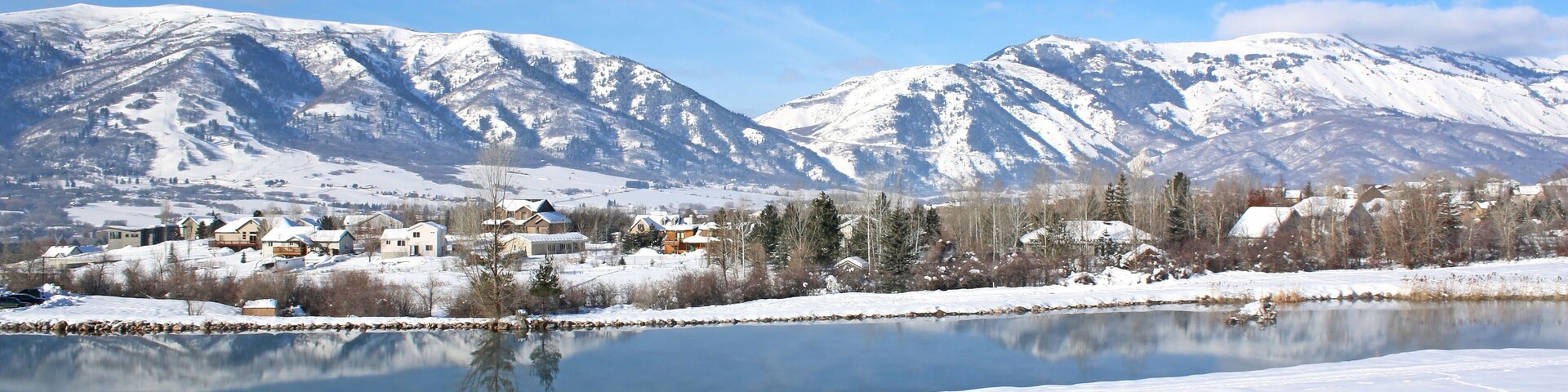 Un paisaje nevado con un lago, montañas y un pueblo pequeño.