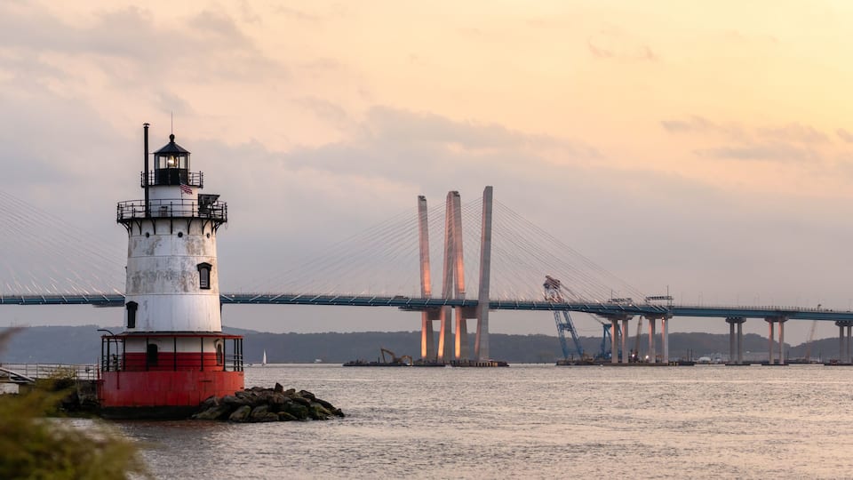 A lighthouse and a bridge over water.