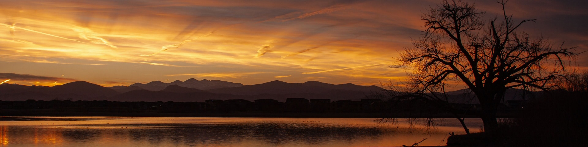 A sunset over a calm lake with mountains in the background.
