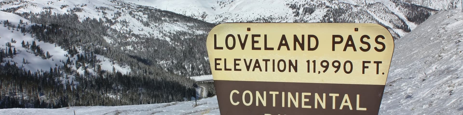 the iconic loveland pass sign and surrounding mountains in winter at at the snowy summit of loveland pass in the rocky mountains of Colorado