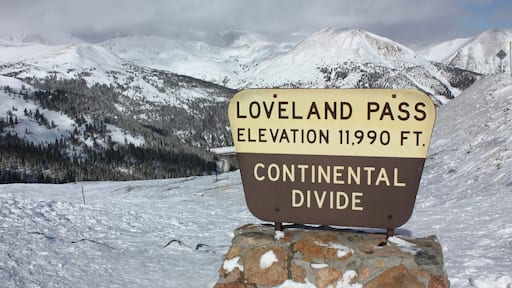 the iconic loveland pass sign and surrounding mountains in winter at at the snowy summit of loveland pass in the rocky mountains of Colorado