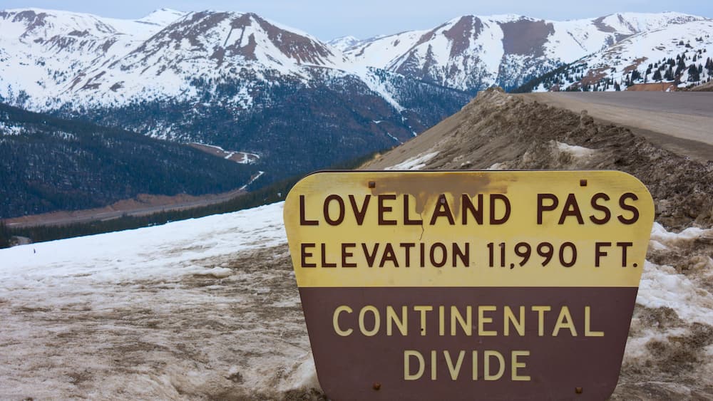 Sign marking Loveland Pass Continental Divide in Colorado Rocky Mountains with snow covered peaks in the background