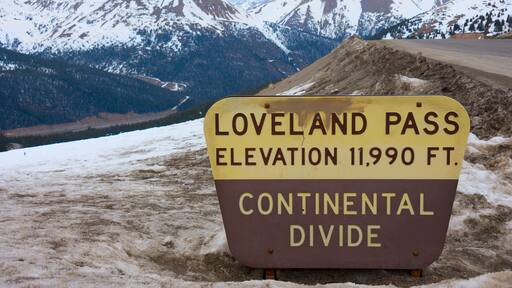 Sign marking Loveland Pass Continental Divide in Colorado Rocky Mountains with snow covered peaks in the background