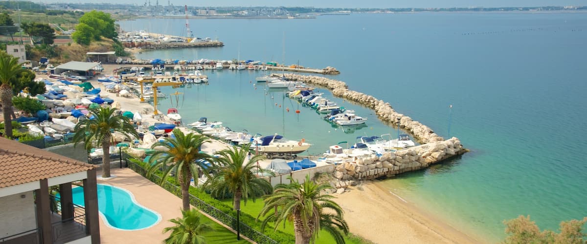 A marina with boats docked, a swimming pool, and a beach.