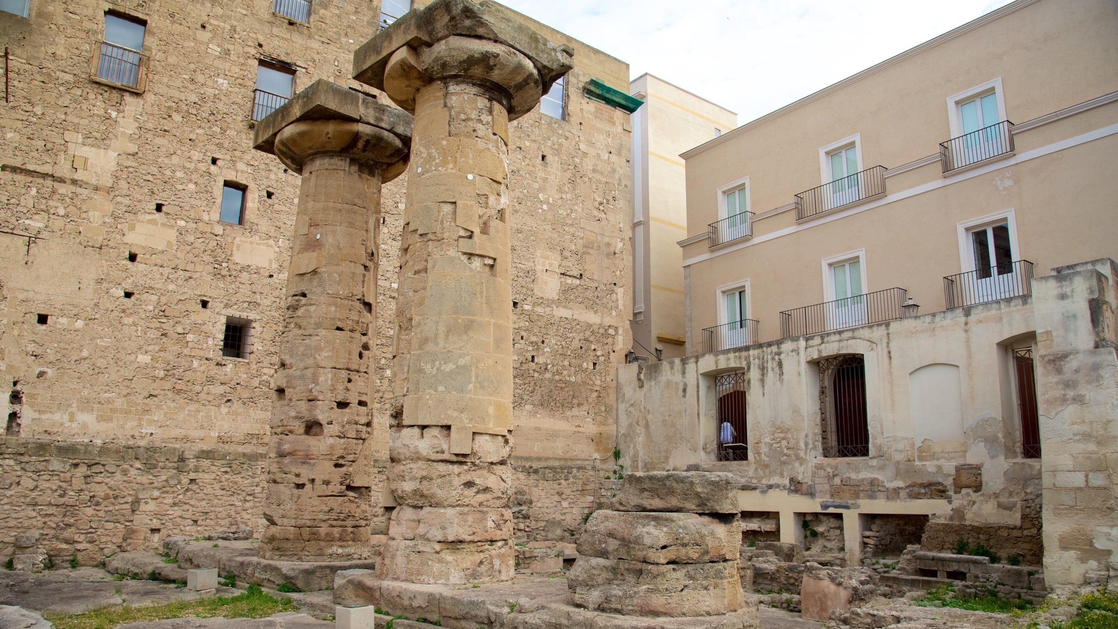 Ancient stone columns, a weathered building, and a modern apartment building.