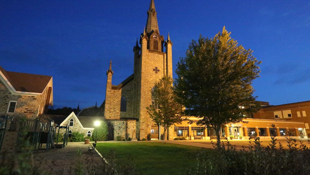 A church with a tall spire and a clock tower at dusk.